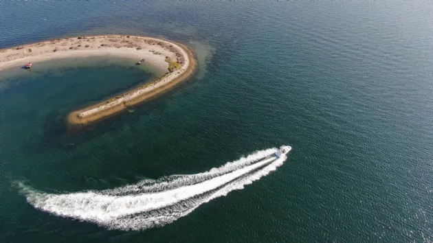 Boat Speeding Away from Horseshoe Island next to Crown Point Beach